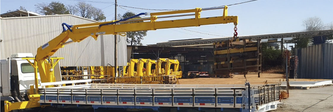 Guindaste articulado em caminhão em área industrial, equipamento usado em operações de içamento que exigem manutenção preventiva para manter desempenho e segurança.