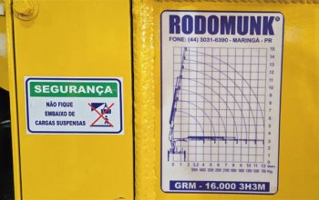Tabela de carga de guindaste instalada no equipamento com gráfico de alcance e capacidade de içamento.