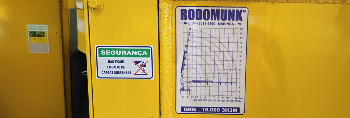 Tabela de carga de guindaste instalada no equipamento com gráfico de alcance e capacidade de içamento.